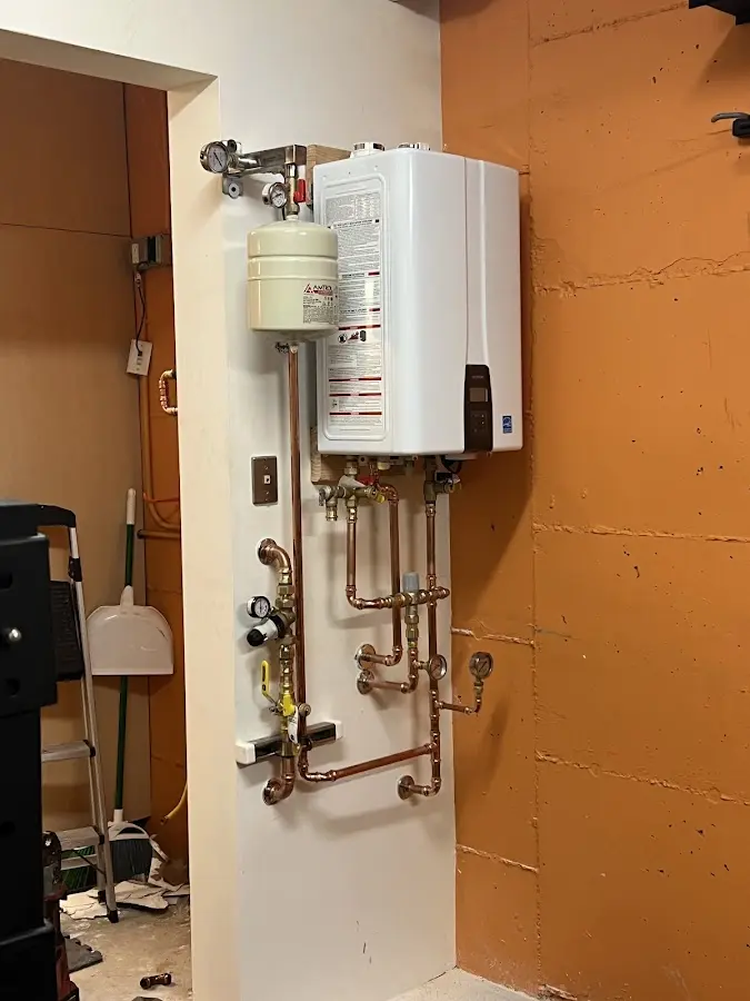 Plumbing technician inspecting water heater connections in Red Bank